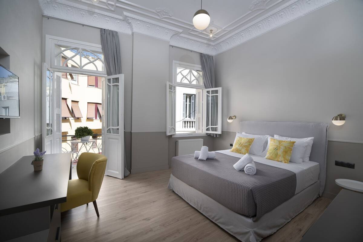 Une chambre à coucher avec un lit, un bureau, une chaise et une vue sur l’extérieur.