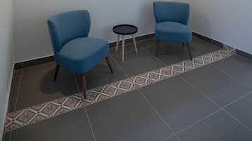 Una habitación con dos sillas azules, una mesa redonda pequeña y dos lámparas colgantes.