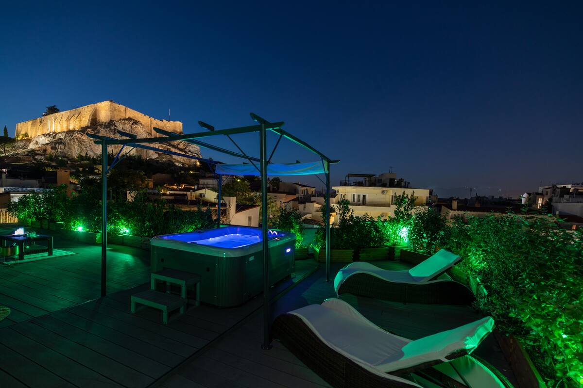 Une terrasse sur le toit dotée d’un jacuzzi, de chaises longues et d’une pergola.