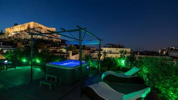 En tagterrasse med jacuzzi, liggestole og en pergola.