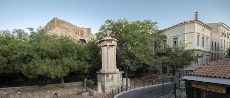 A historical monument surrounded by trees and a street with buildings.