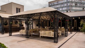 An outdoor seating area with a gazebo, tables, and chairs. - Dunav Plaza Hotel (Ruse)