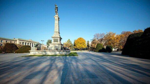 A large open plaza with a central monument, surrounded by trees and a building with columns. - Dunav Plaza Hotel (Ruse)