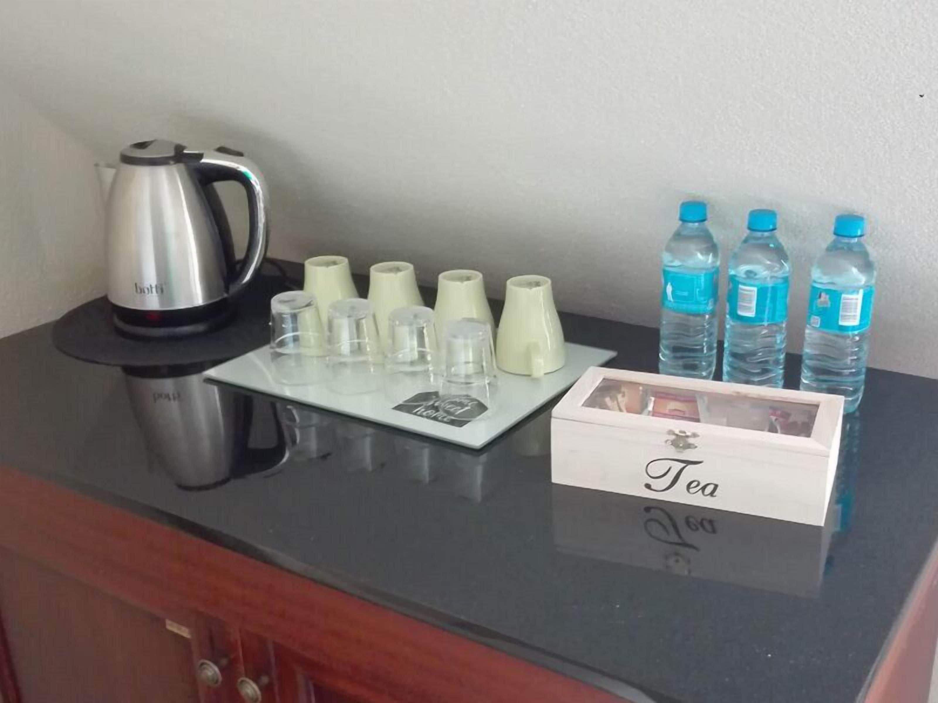 A kitchen counter with a tea station, including a kettle, cups, and water bottles.