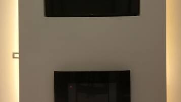 Una pared con dos objetos rectangulares negros, posiblemente dispositivos electrónicos, colocados a diferentes alturas.