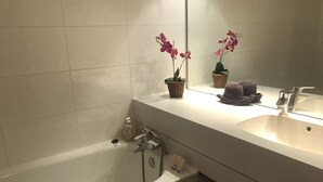 A bathroom with a white bathtub, a sink, and two potted orchids on the counter. - Marches 25 - 3 room duplex apartment, overlooking the slopes (LES AVANCHERS VALMOREL)