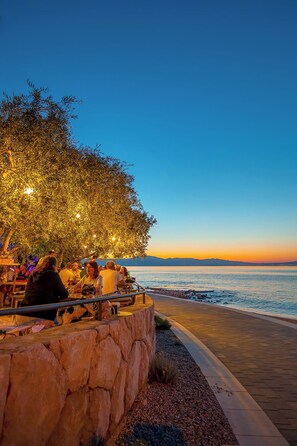 Un espace extérieur aménagé avec des murs en pierre et offrant une vue sur la mer au coucher du soleil.