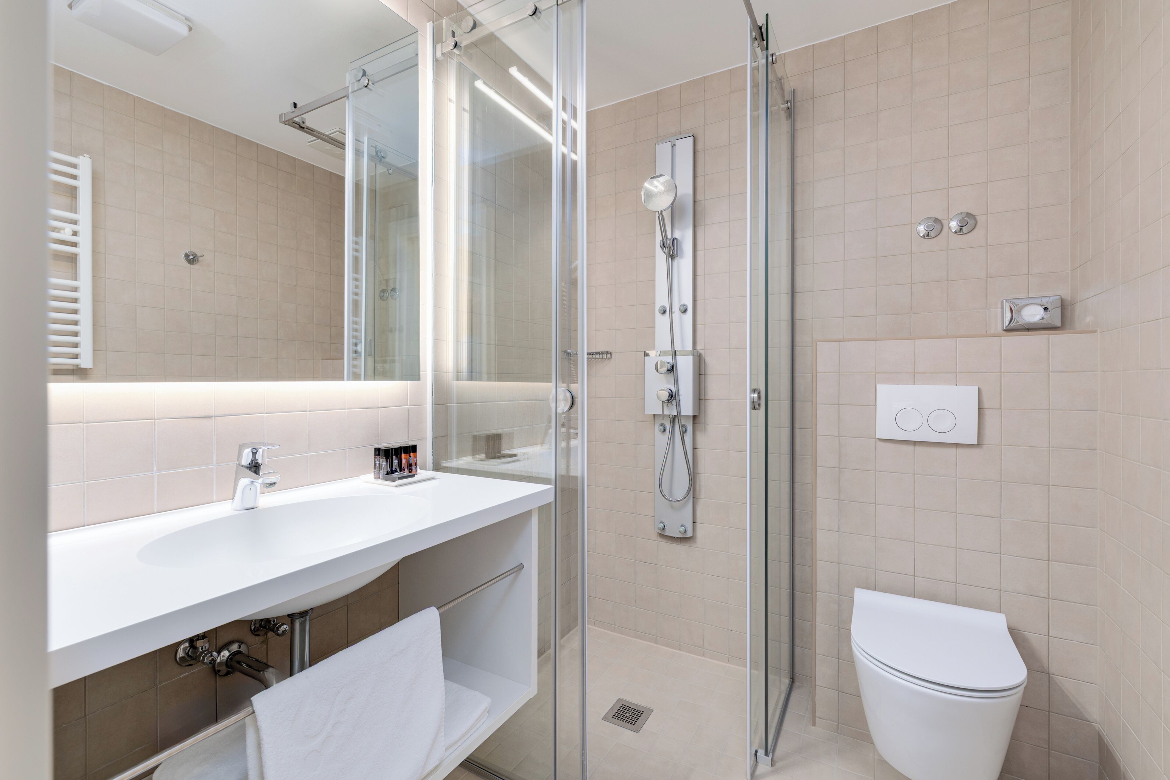 Ein modernes Badezimmer mit einer gläsernen Duschkabine, einem weißen Waschbecken und einer Toilette.