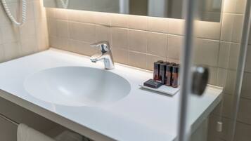 Un baño con un lavabo blanco, una llave moderna y un espejo encima.