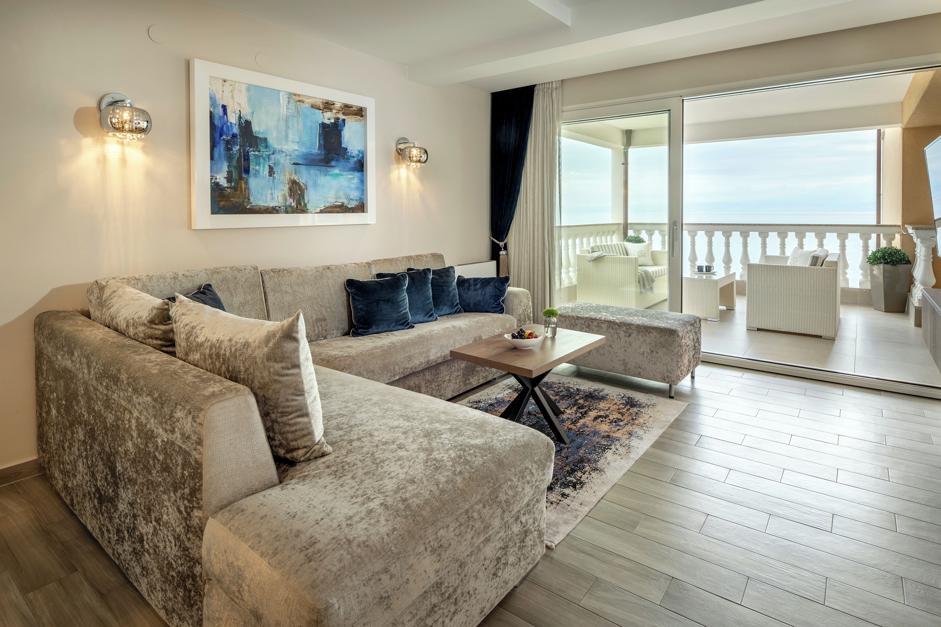 Un salon moderne avec un canapé d’angle, une table basse et un balcon aménagé avec du mobilier d’extérieur.