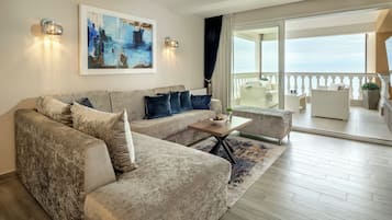 Un salon moderne avec un canapé d’angle, une table basse et un balcon aménagé avec du mobilier d’extérieur.