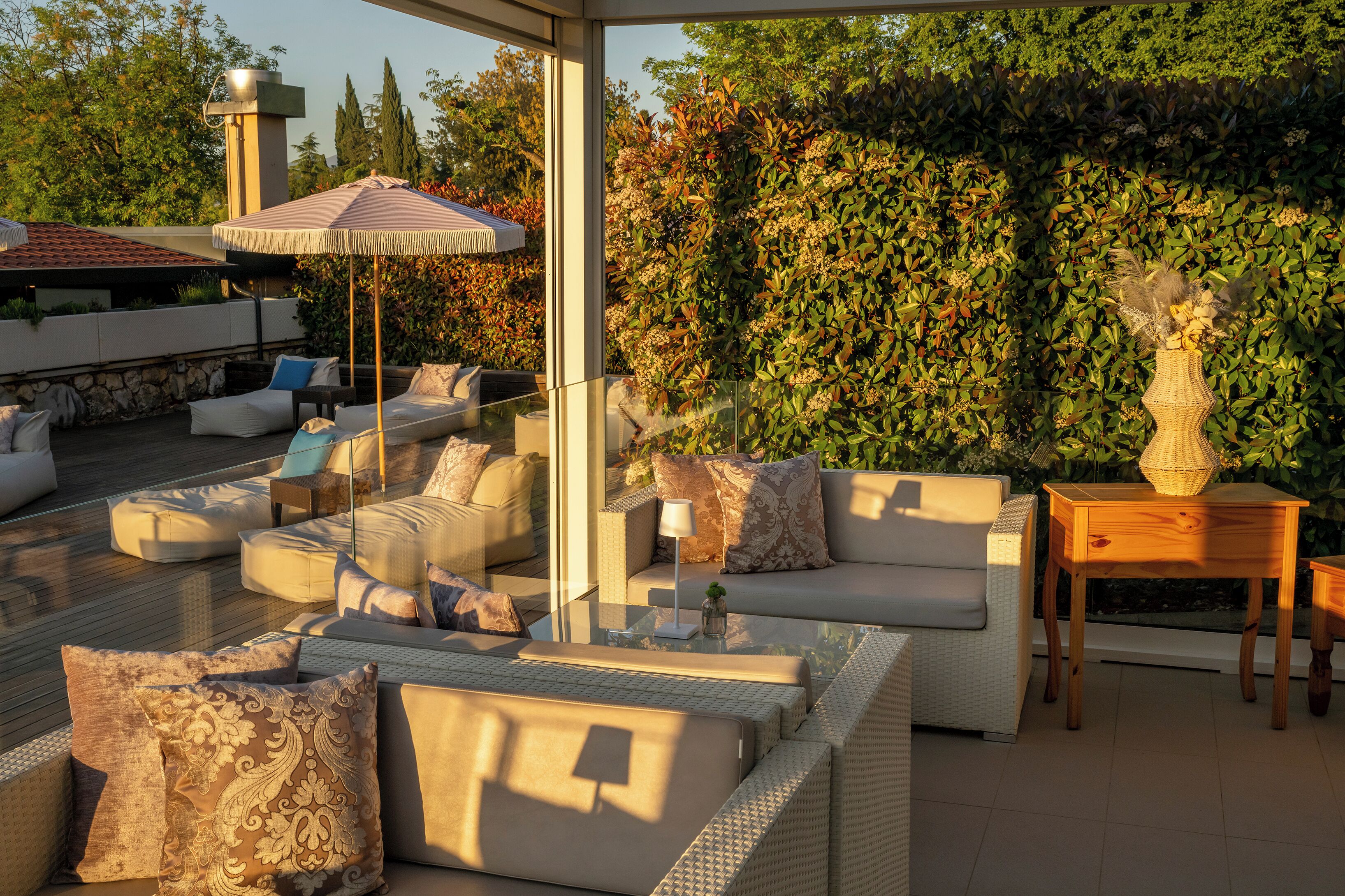An outdoor seating area with wicker furniture, a glass table, and a decorative vase.