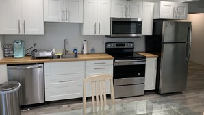 Uma cozinha moderna com armários brancos, eletrodomésticos de aço inoxidável, micro-ondas, fogão e geladeira.