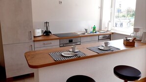 A modern kitchen with a wooden countertop, a built-in oven, and a window providing natural light. - Ferienwohnung STADTOASE Apartmenthaus (Frankenberg)