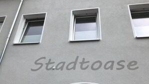 A building facade with the word "Stadtoase" painted on it, featuring three windows and a door. - Ferienwohnung STADTOASE Apartmenthaus (Frankenberg)
