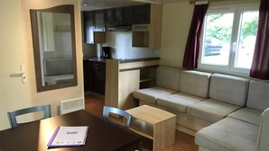 A compact living space with a kitchenette, a dining area, and a seating area with a window.