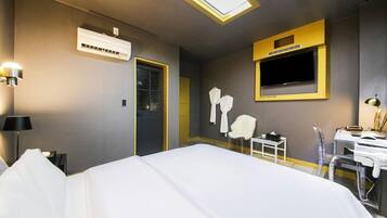 Una habitación de hotel con cama, escritorio, televisor y espejo.