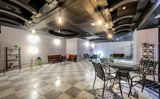 Una amplia sala de reuniones con suelo a cuadros, varias disposiciones de asientos e iluminación colgante.
