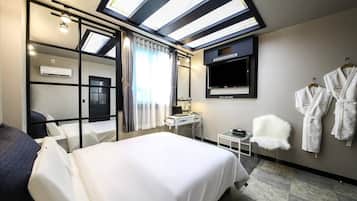A modern hotel room with a large bed, a desk, a flat-screen TV, and a wardrobe.