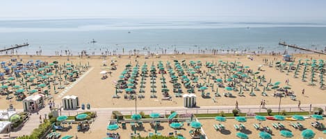 In StrandnĂ€he, schwarzer Sandstrand, LiegestĂŒhle, Sonnenschirme