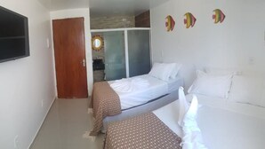 Una habitación de hotel con dos camas, televisión y puerta corredera que da al baño.