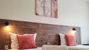 A hotel room with two beds, wooden headboard, wall art, and bedside lamps. - Hotel Sorbona (Varna)