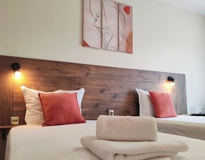 A hotel room with two beds, wooden headboard, wall art, and bedside lamps. - Hotel Sorbona (Varna)