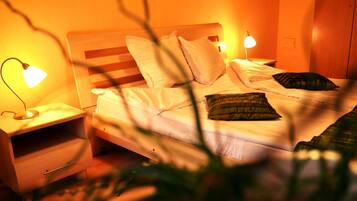 Een net opgemaakt bed met kussens en een bedlampje op een houten nachtkastje.