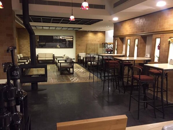 Un interior moderno con zona de bar, asientos y una cocina visible a través de un separador de vidrio.