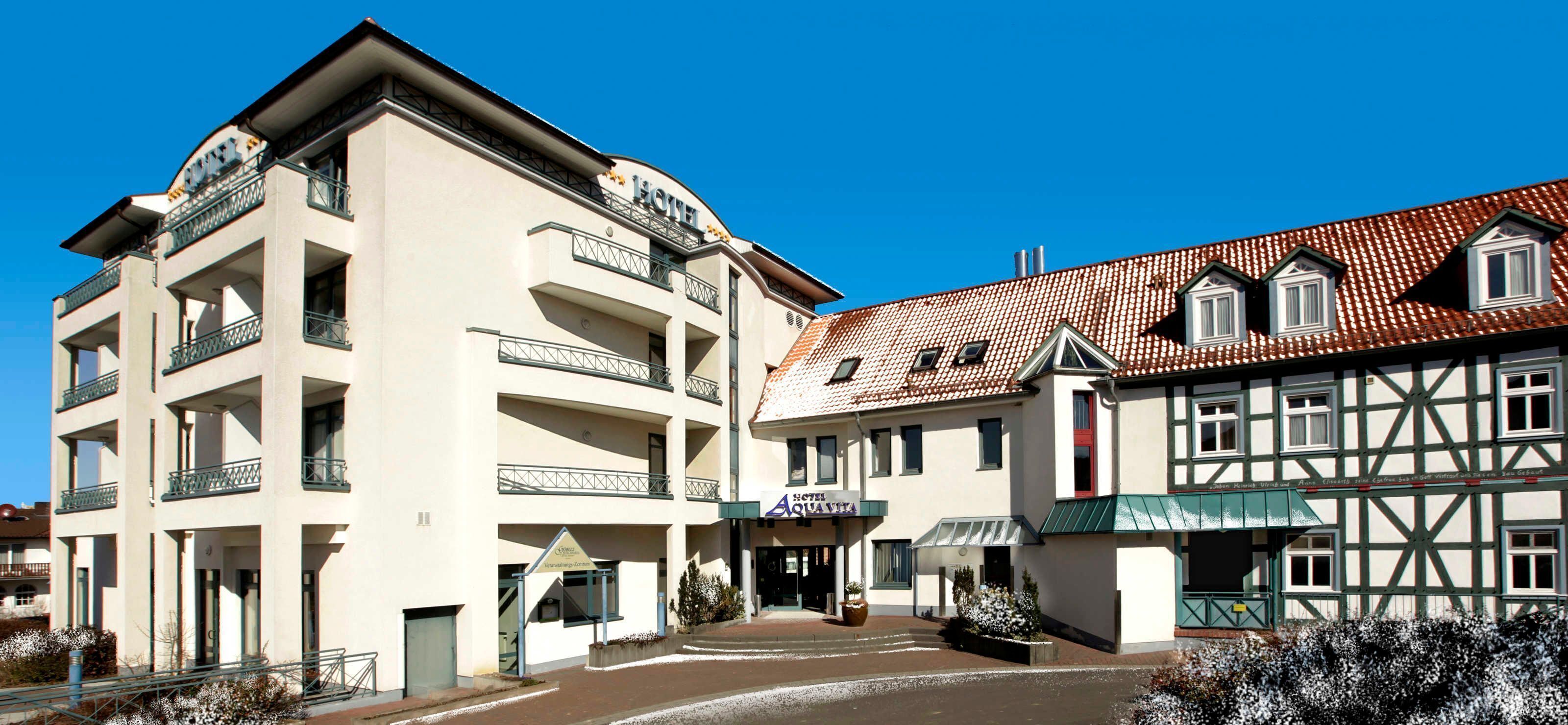 A hotel with a modern facade, multiple balconies, and a traditional building with a tiled roof.