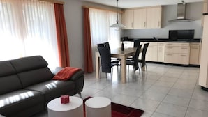 Una sala moderna con un sofá, dos mesitas auxiliares y un comedor con sillas y una mesa.