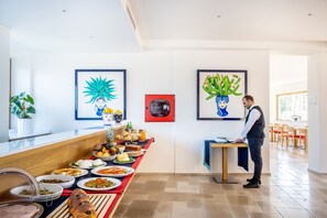 A breakfast buffet with various dishes, a waiter, and artwork on the walls. - Maison Montechiaro (Vico Equense)