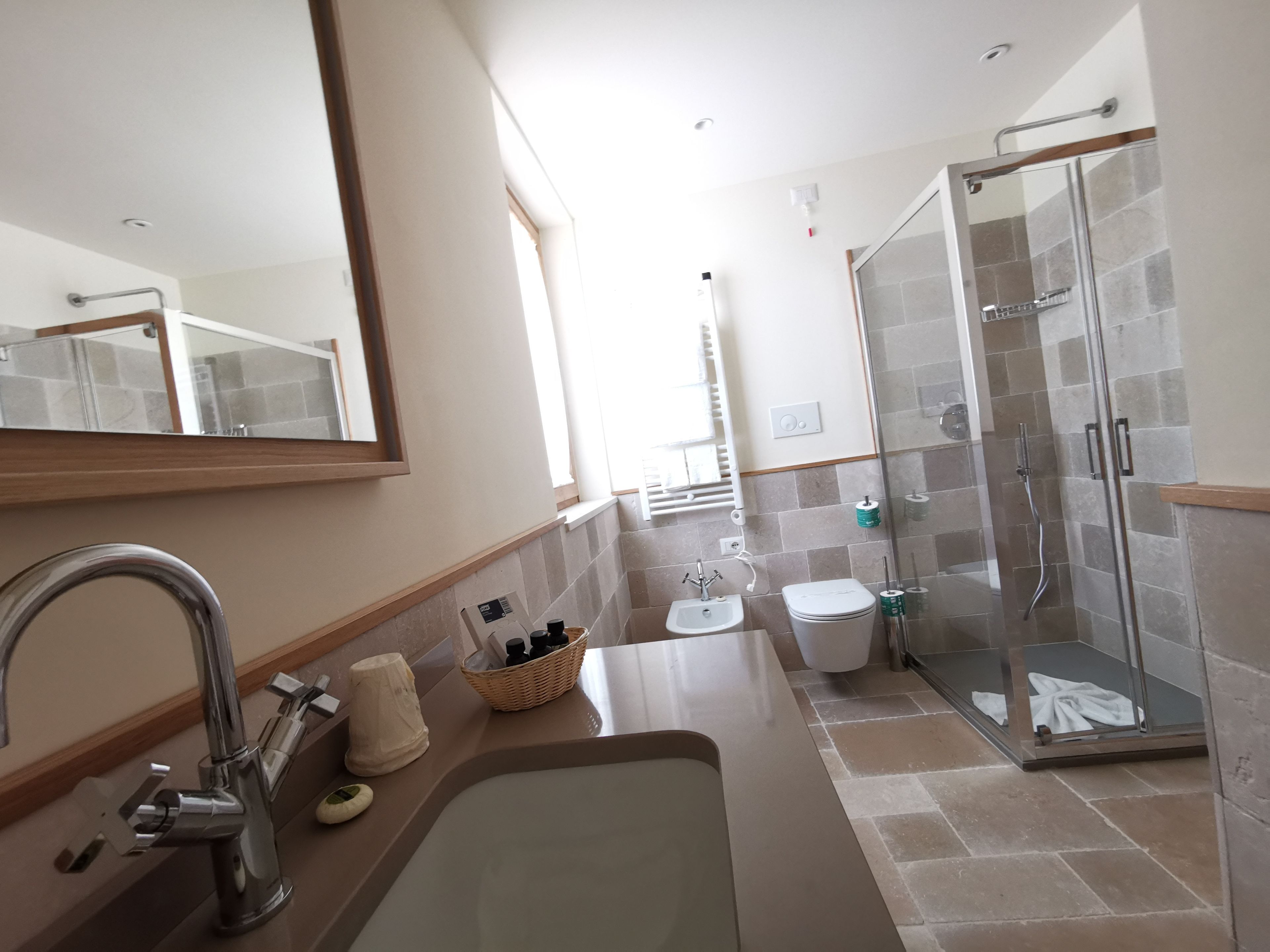 A modern bathroom with a sink, mirror, shower, and toilet.