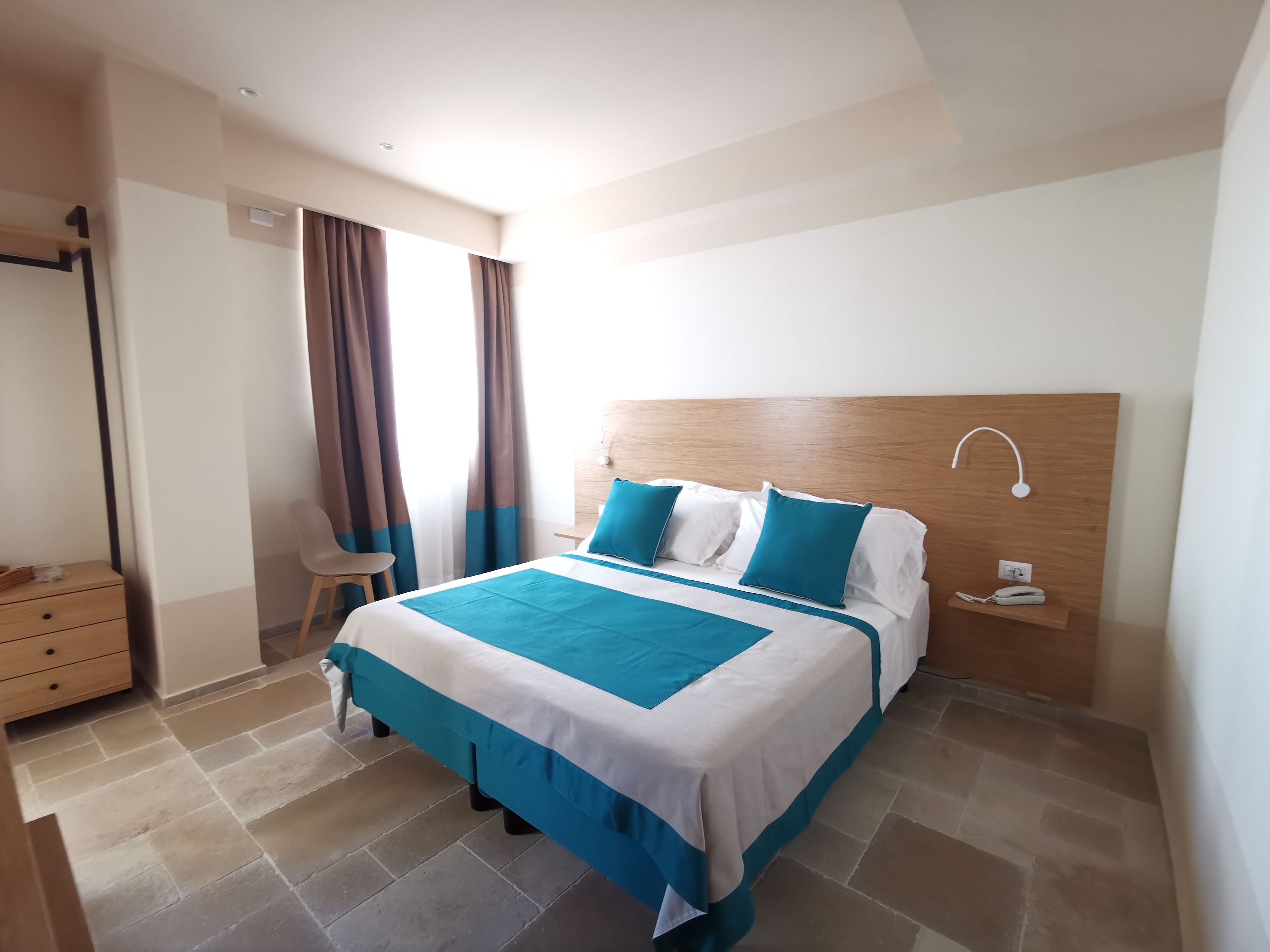A neatly arranged bedroom with a bed, bedside table, and a chair.