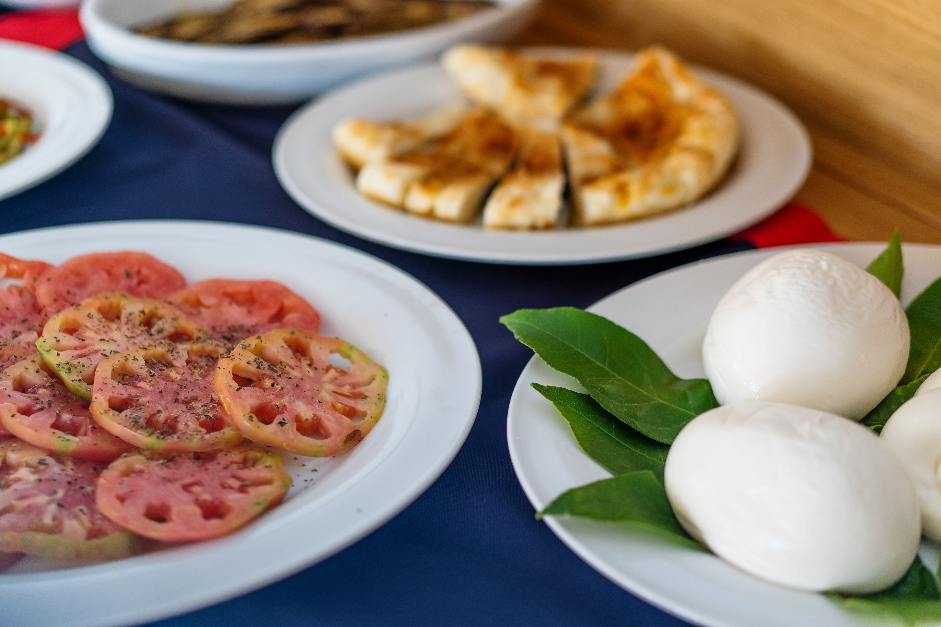 Una mesa con platos de comida, incluyendo tomates y queso mozzarella.