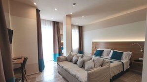 Quarto de hotel moderno com sofá-cama, escrivaninha e mesa de cabeceira.