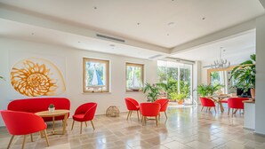 Quarto espaçoso com uma pintura grande, cadeiras vermelhas, uma mesa de madeira e vista para o verde lá fora.