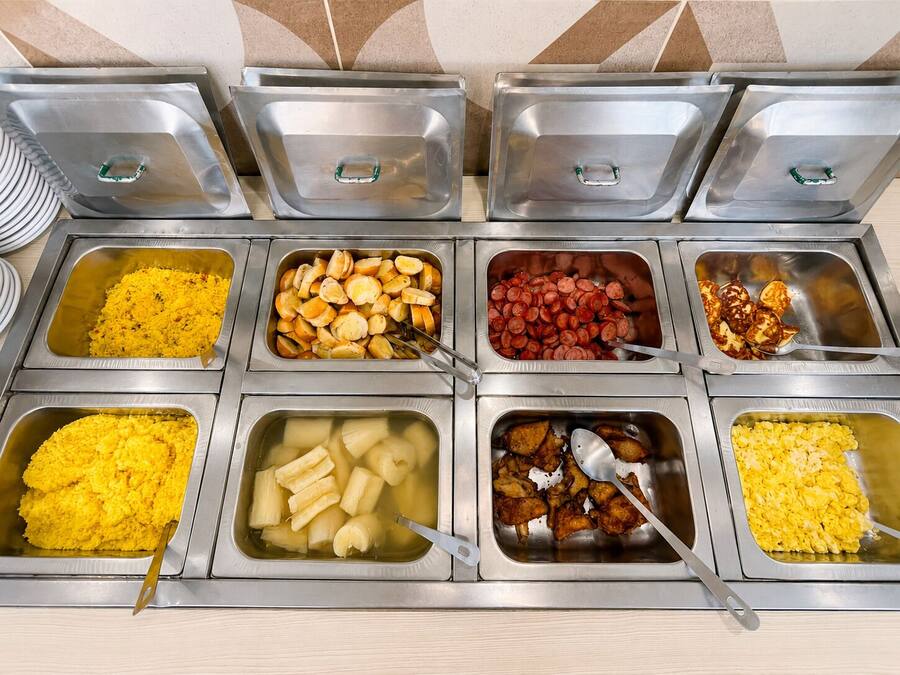 Un bufé con diversas opciones de comida, incluyendo arroz, pan, frijoles y pollo.