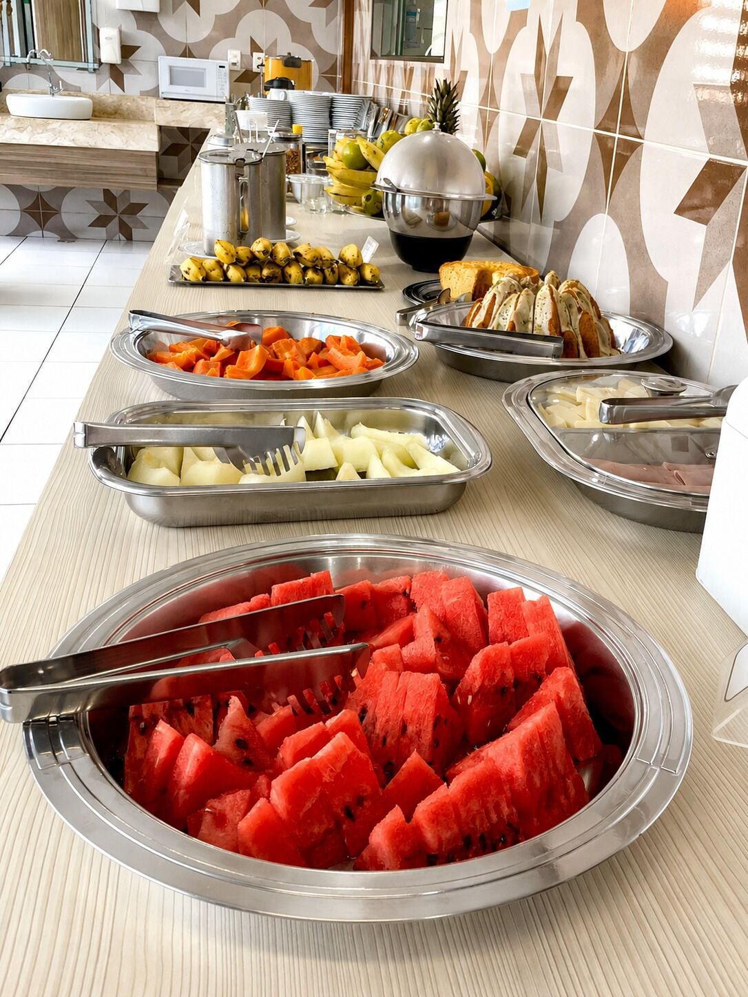 A buffet with various food items including watermelon, bananas, and cheese.