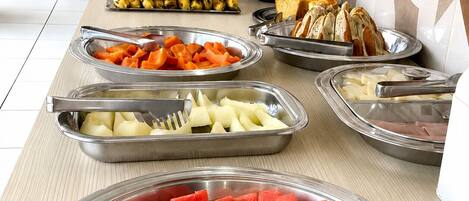 A buffet with various food items including watermelon, bananas, and cheese.
