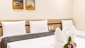 A hotel room with a bed, two wall-mounted paintings, and a bouquet of flowers on the bed. - Hotel Nacional (Arapiraca)