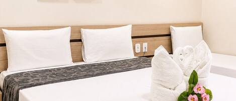 Habitación de hotel con una cama, dos cuadros en la pared y un ramo de flores sobre la cama.