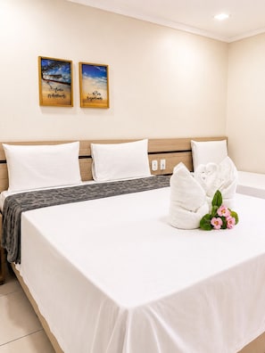 A hotel room with a bed, two wall-mounted paintings, and a bouquet of flowers on the bed. - Hotel Nacional (Arapiraca)