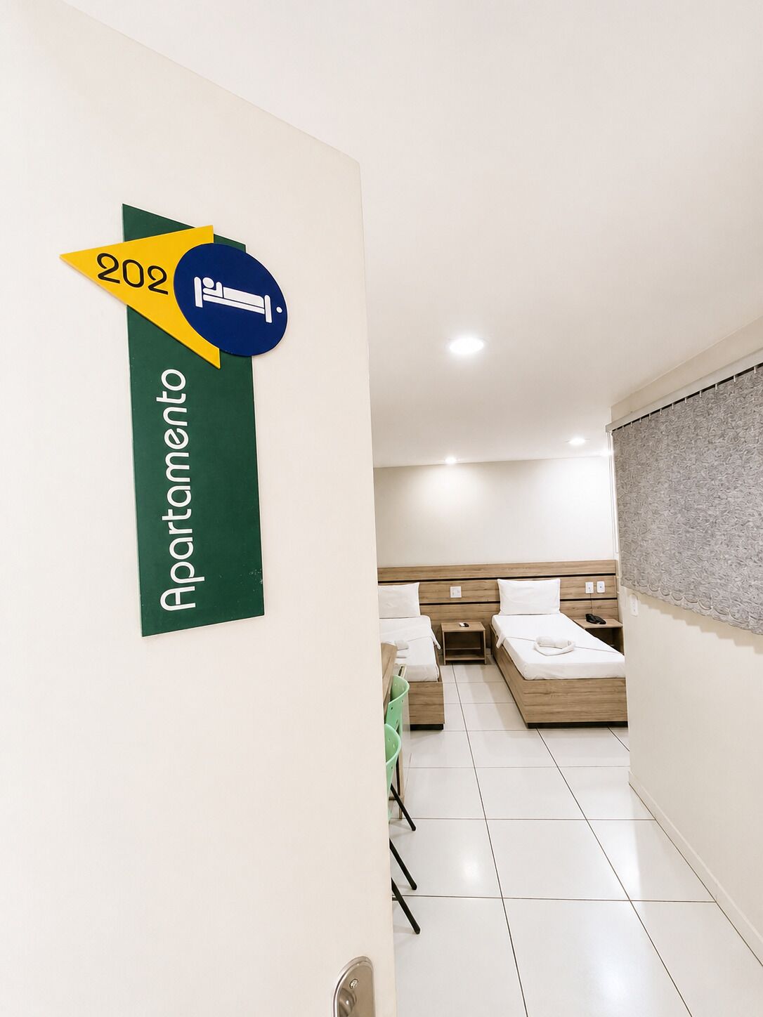 Une chambre d’hôtel avec un lit, des tables de chevet et une salle de bain visible à travers une porte ouverte.