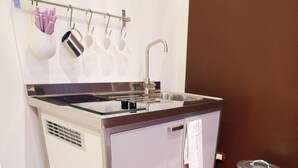 Een kleine keuken met een roestvrijstalen spoelbak, een klein aanrecht en een prullenbak.