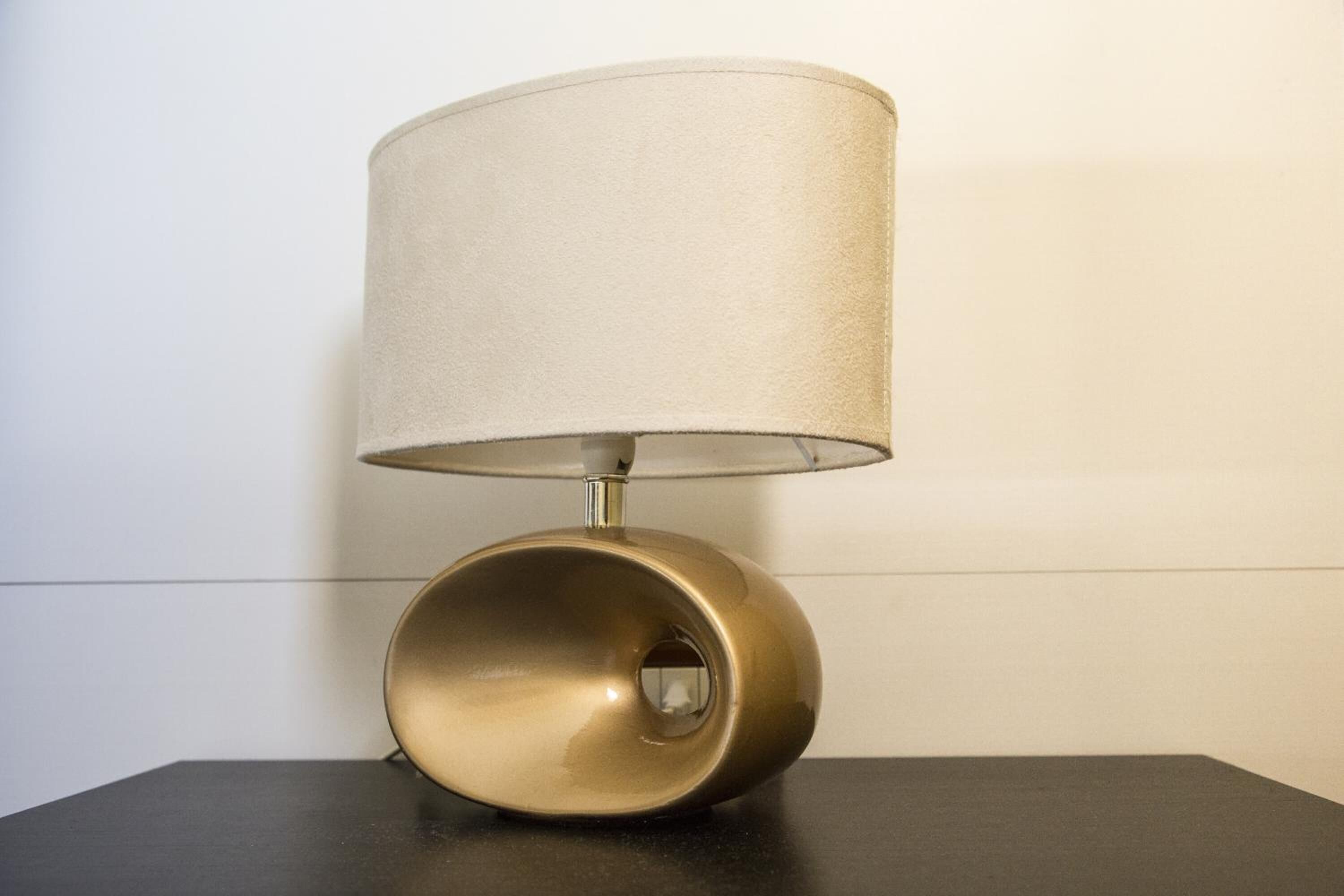 Una lámpara de mesa moderna con pantalla cilíndrica y base metálica.