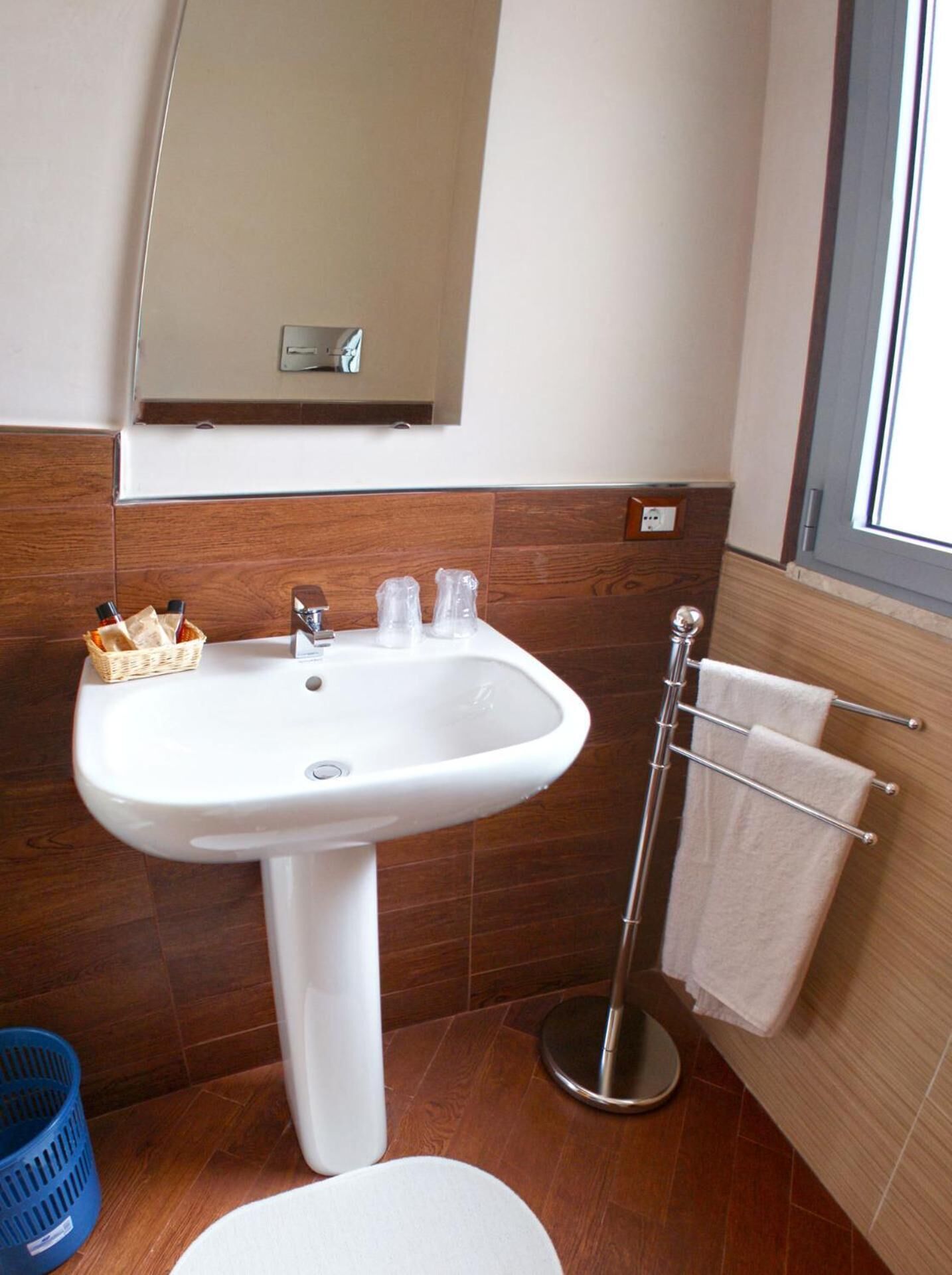 A bathroom with a white pedestal sink, a mirror above it, and a towel rack with towels.