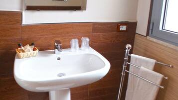 A bathroom with a white pedestal sink, a mirror above it, and a towel rack with towels.