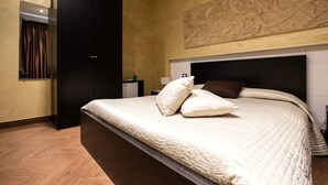 Een slaapkamer met een groot bed, een kledingkast, een bureau en een kunstwerk aan de muur.