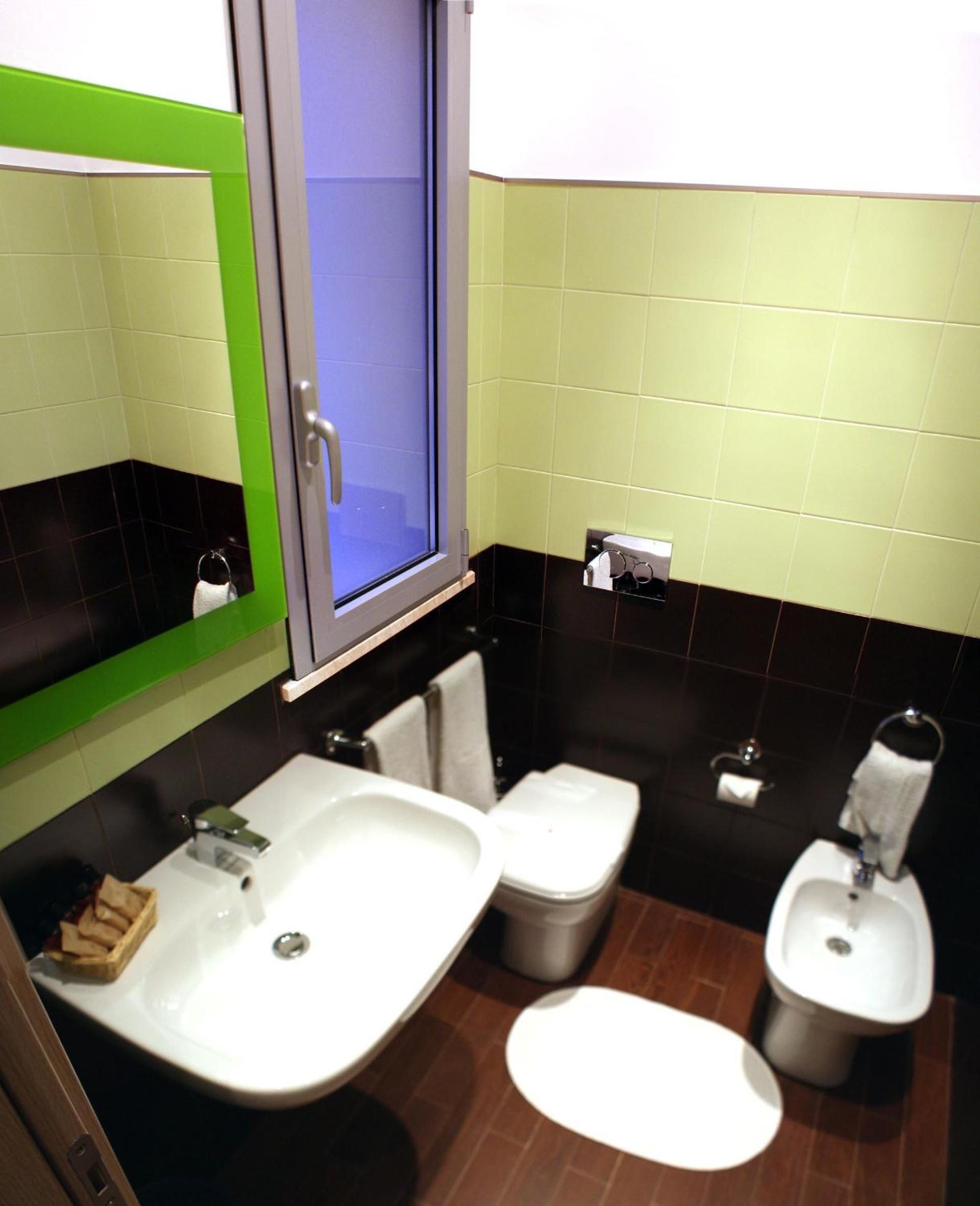 A bathroom with two sinks, a toilet, and a bidet.